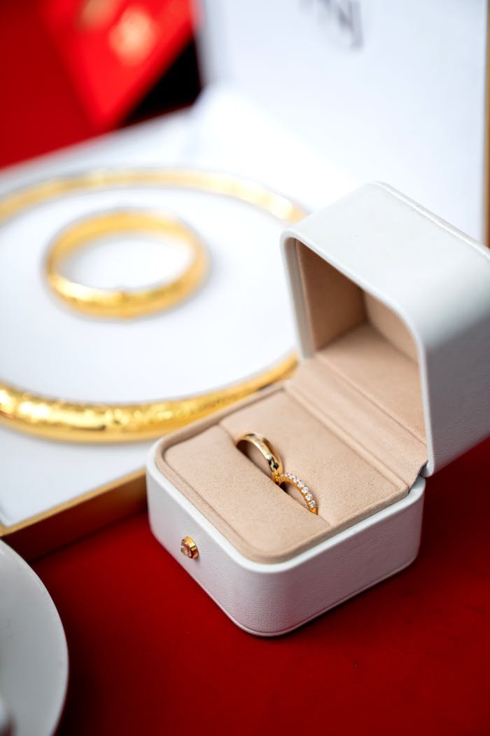 A luxurious gold ring in an elegant box with matching bracelet on a red background.